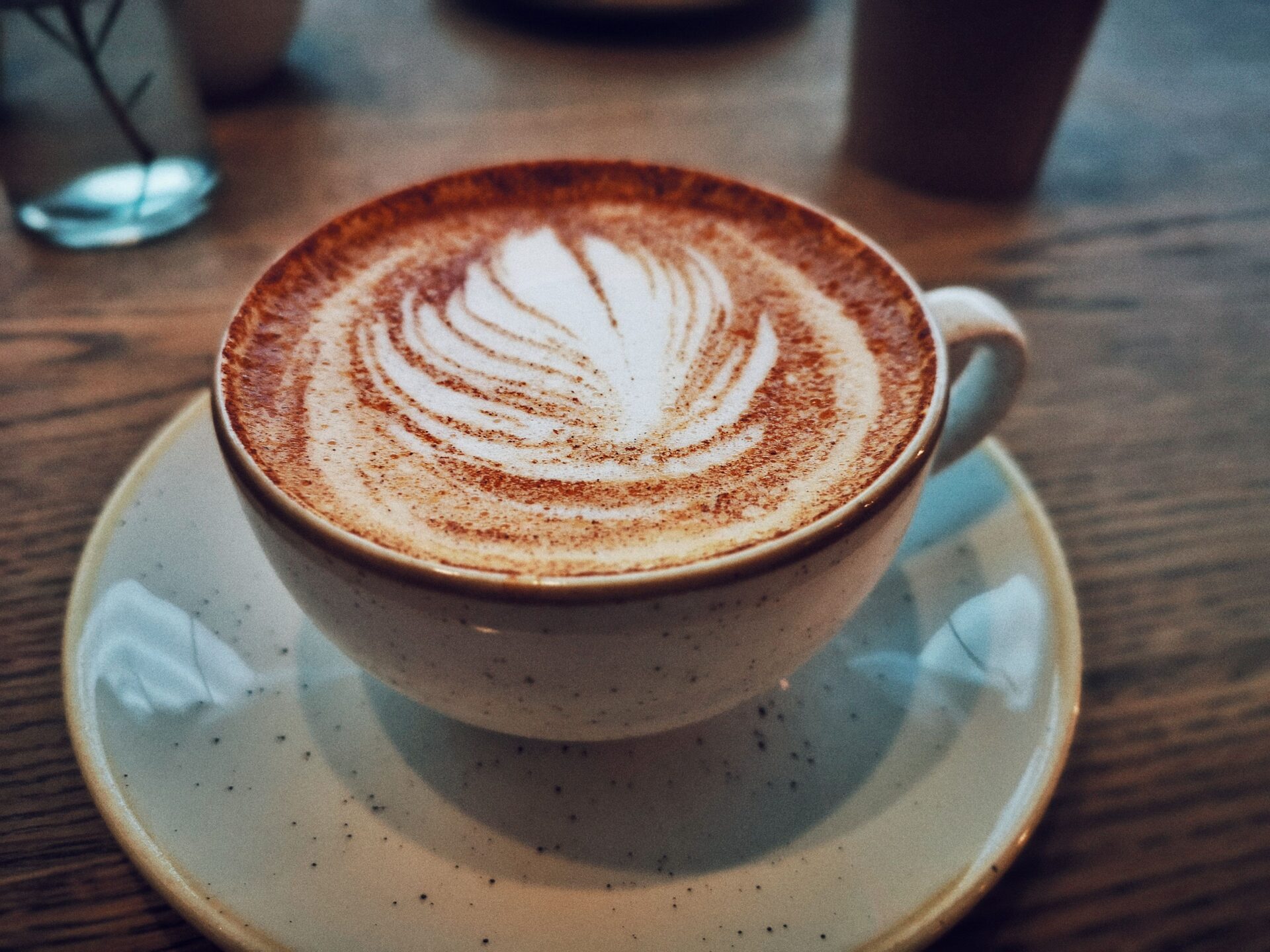 Cappuccino avec un dessin de feuille dans la mousse, dans une tasse en céramique sur sa soucoupe