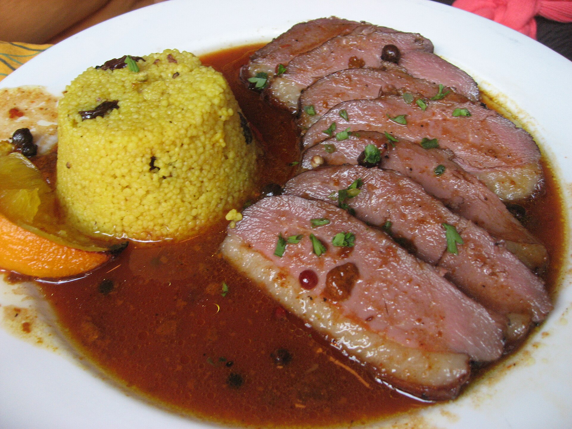 Tranches de magret de canard rosé nappées de sauce, servies avec un accompagnement